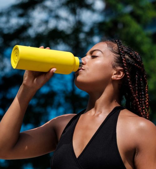 Attractive,Young,Woman,Drinking,From,A,Yellow,Bottle.,She,Is