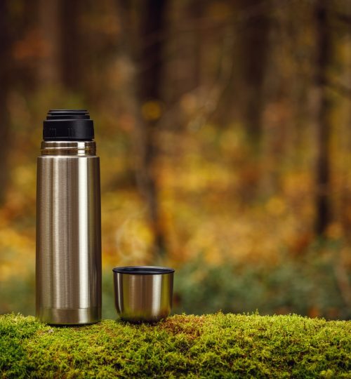 Steel,Thermos,With,Delicious,Hot,Tea,On,An,Old,Mossy