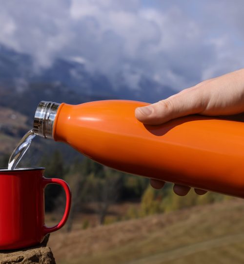 Woman,Pouring,Hot,Water,Into,Mug,In,Mountains,,Closeup